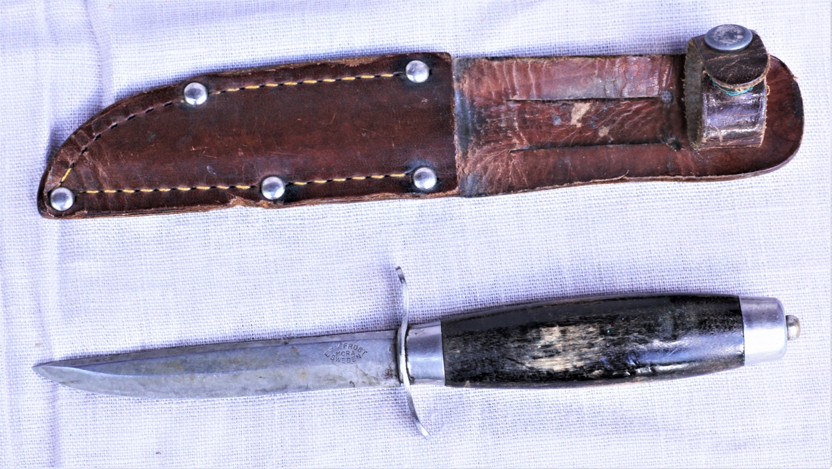Kniv (a) med svart treskaft og (b) slire av skinn.