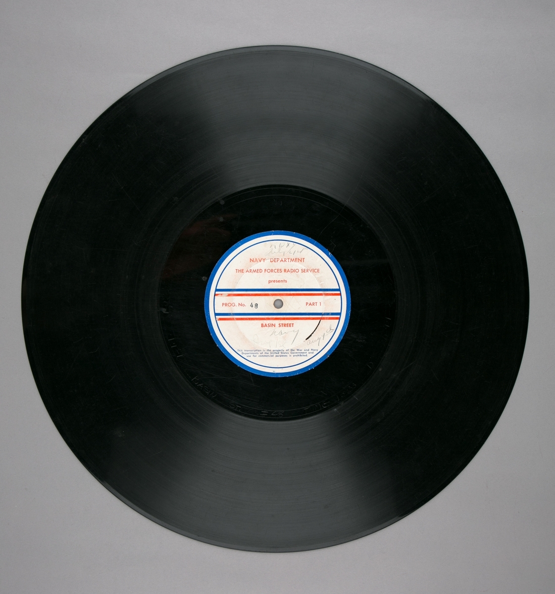 Grammofonplatesamling. LP-plate med tittel "The Armed Forces Radio Service" utgitt av Navy Department. Plate i svart vinyl spilles på platespiller med 33 1/3 omdreininger i minuttet (33-plate).