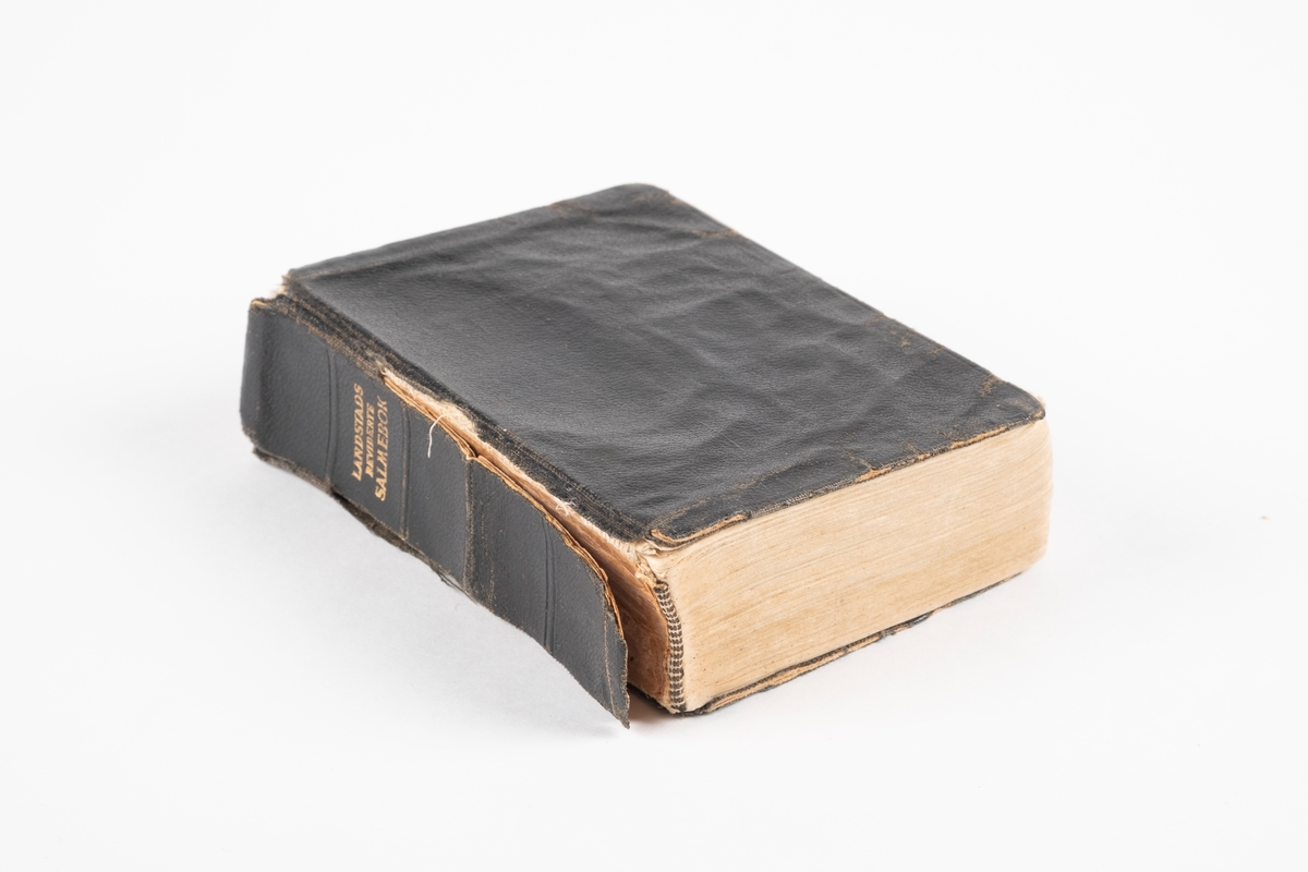 En salmebok med svart omslag av papp og tekstil. De siste sidene i boken består av signaturer.