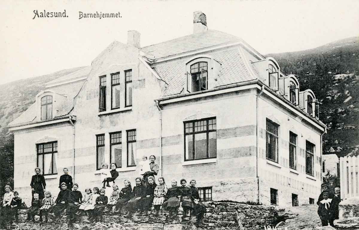 Prospektfotografi av Ålesunds barnehjem på Klipra. Foran bygningen står flere barn og ansatte oppstilt for fotografen.