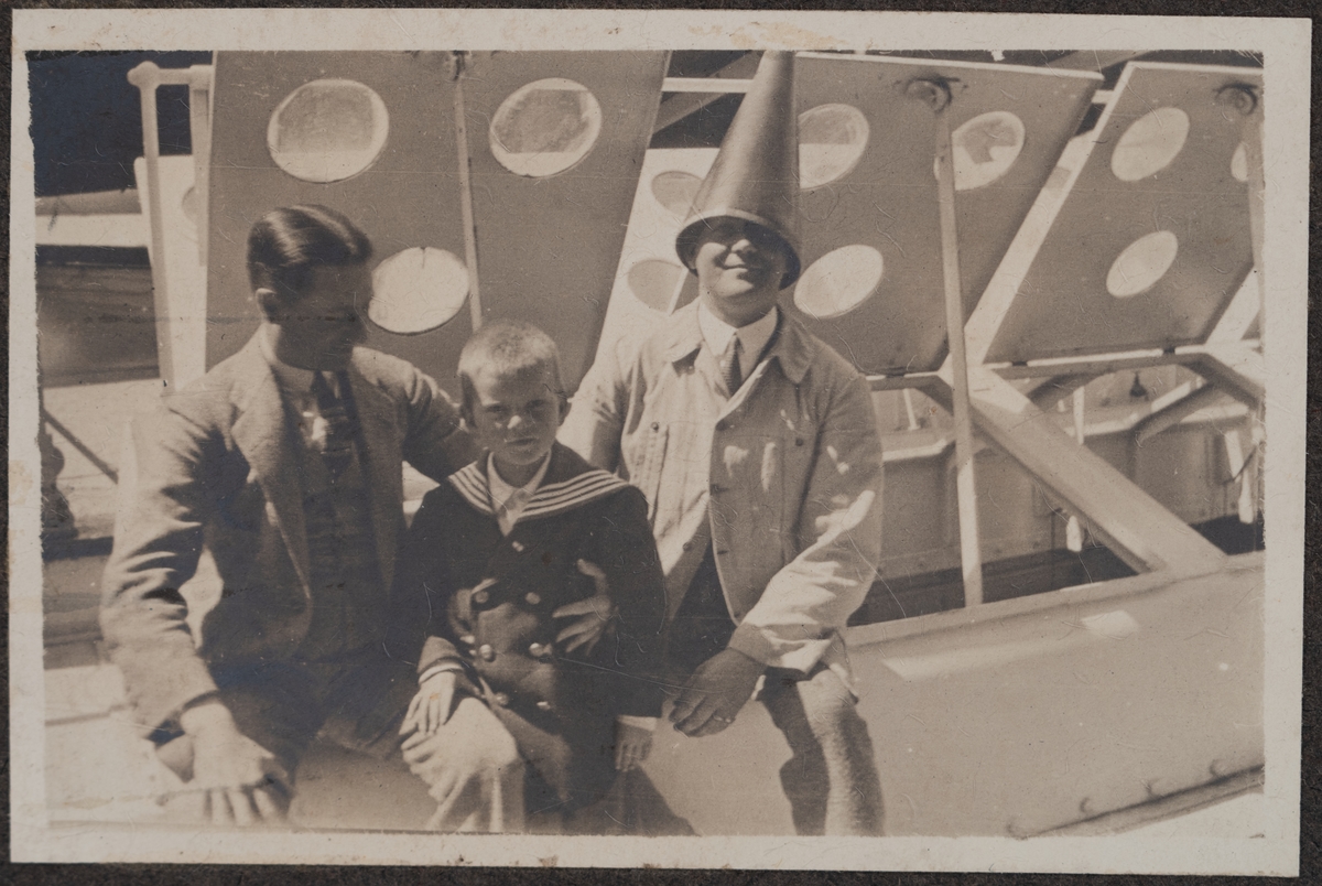 Gösta Grundberg tillsammans med två män på soldäck. Den ena av männen har en tratt på huvudet.
Bildtext: "Three men in a boat."