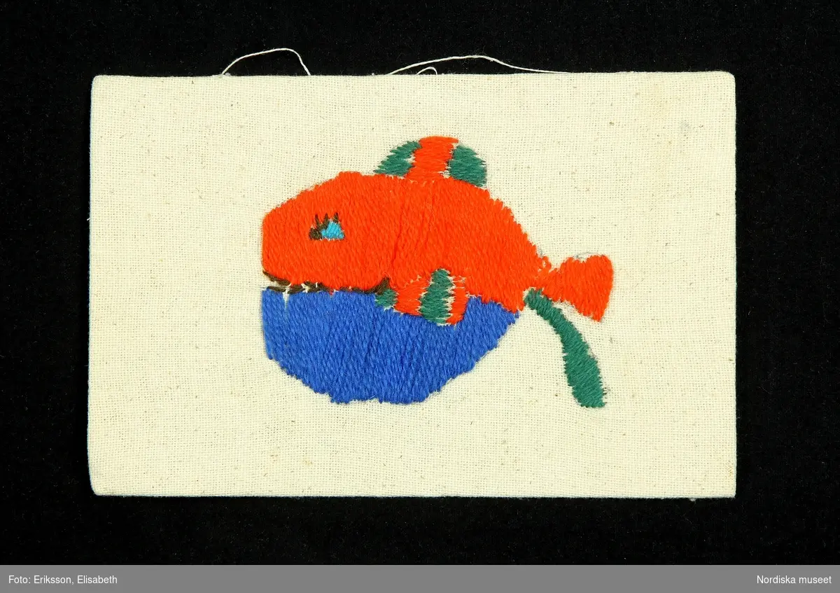 Fisk med huvudet riktat åt vänster. Övre halvan orange, undre halvan blå, fenorna orange- och grönrandiga.
