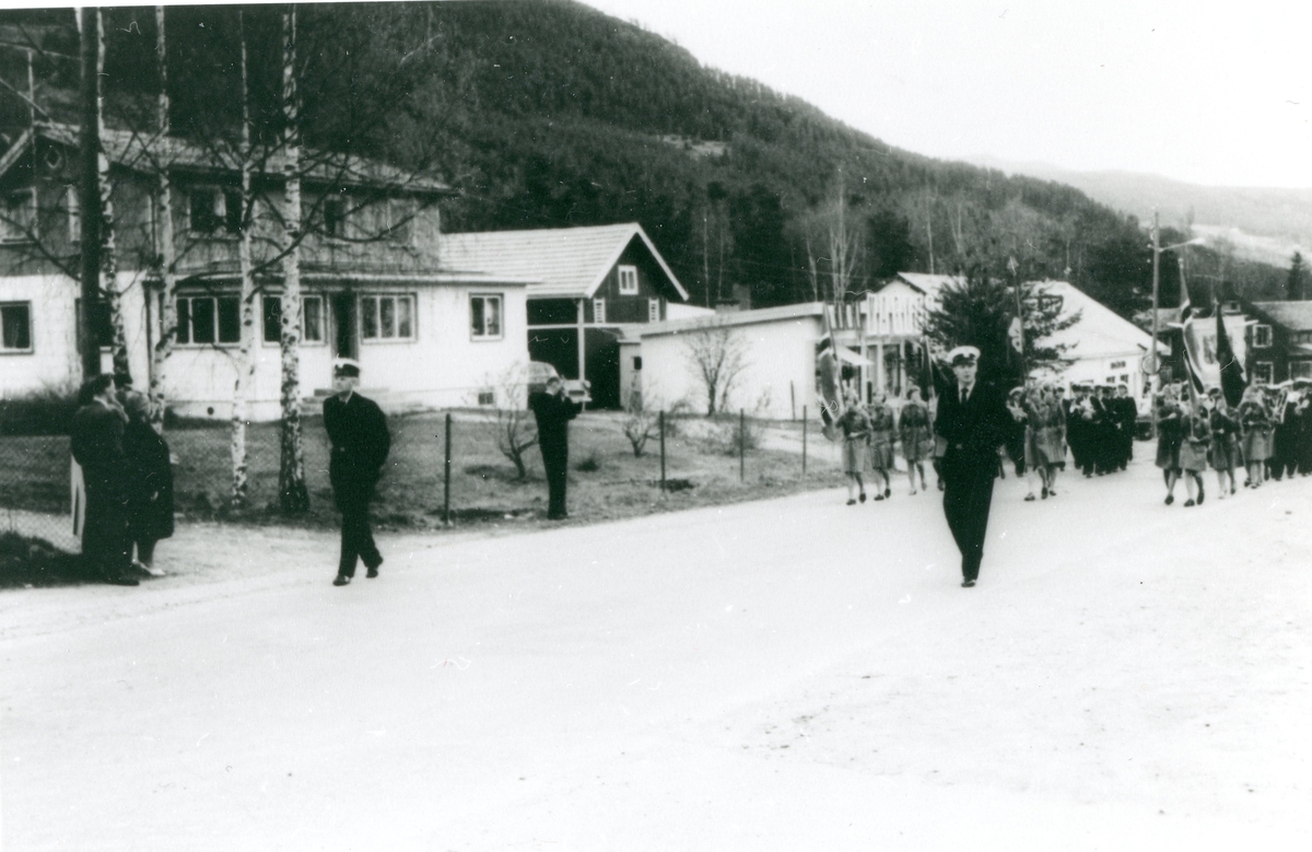 Gruppe,politi,faner og flagg.
17 mai på Gol i 1960 åra.
Framom toget går til v.:Halvor Bruserud og Ingvald Kleven.
I bakgrunnen ligg huset til Faråsen.