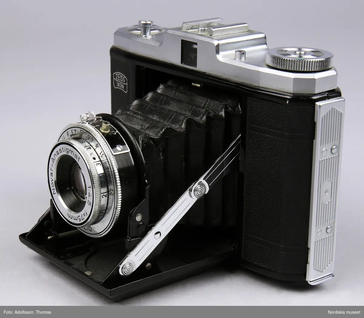 Svart bälgkamera för 60 mm bred rullfilm av märket Zeiss Ikon. Modell Nettar 518/16. Kameran har ett svart hölje av plast. Ovandel i lättmetall.  
Johanna Skoglund 2013-04-02