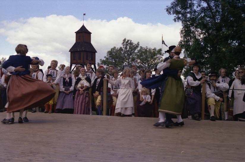 Folkdans på dansbanan vid friluftsmuseet på Grännaberget, det är den så kallade Grännapolkan. I bakgrunden skymtar klockstapeln.