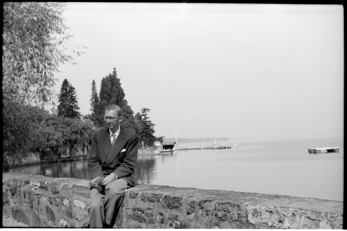 Lennart Welander sitter på muren vid Genèvesjön.