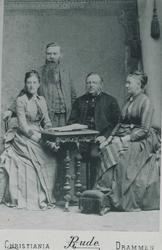 Familiegruppe med to kvinner og en mann som sitter ved et bo