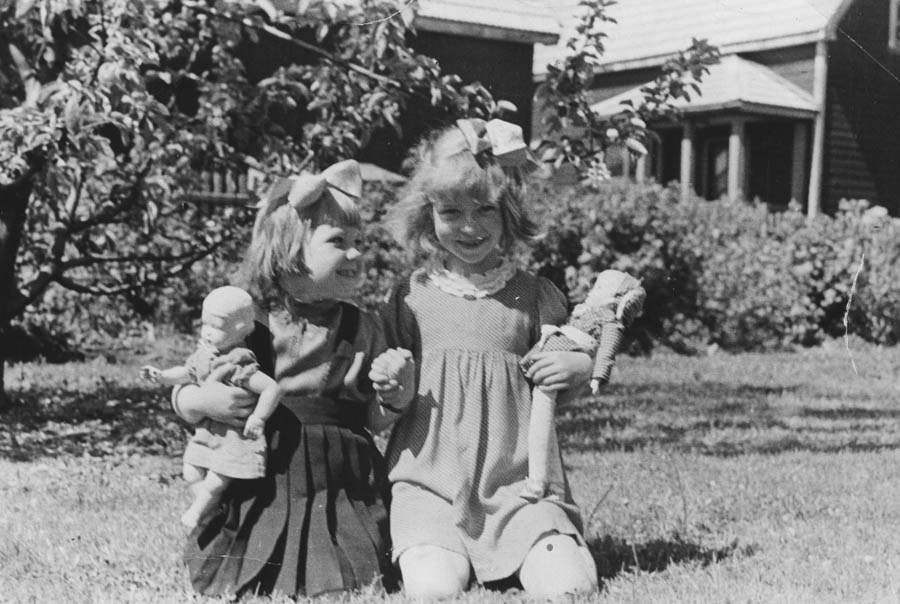 To små jenter på gresset med dukkene.