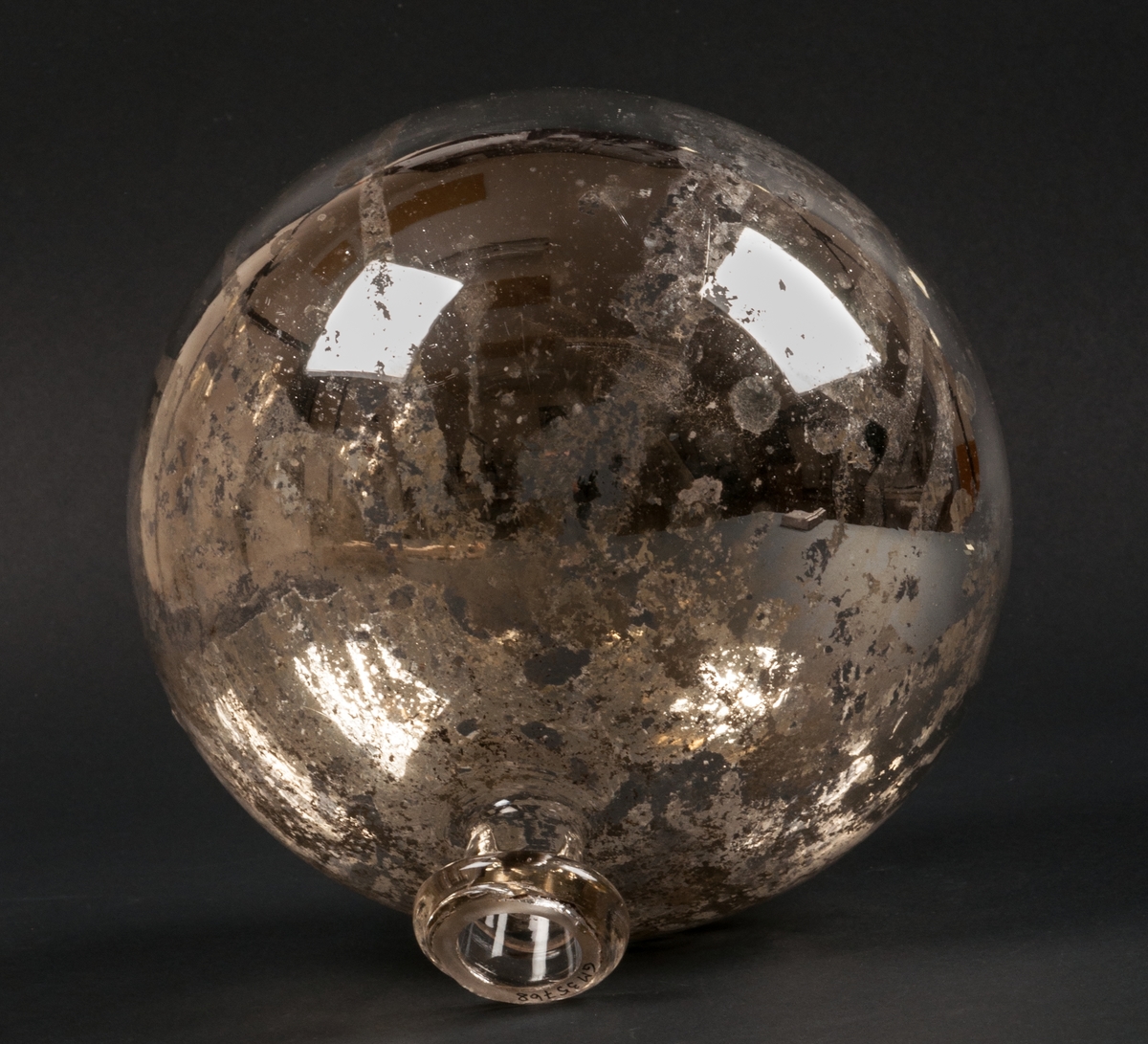 Trädgårdsprydnad i form av handblåst, silverfolierad glaskula som vilar i en "vas" av samma material. Förmodligen har kulan använts som trädgårdsprydnad utomhus. Kulan är med stor sannolikhet tillverkad vid Gefle Glasbruk vid Västra Löten i Gävle strax efter sekelskiftet 1900.