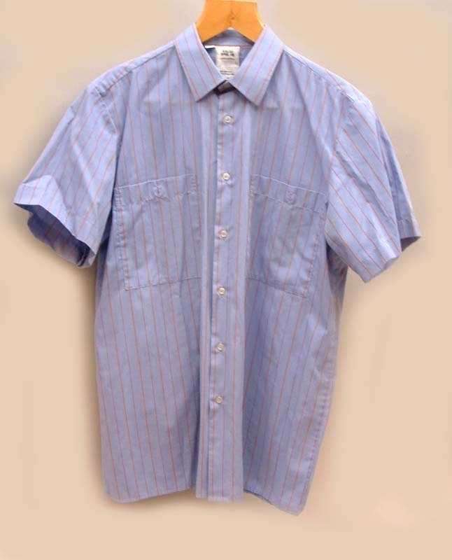 Skjorta med kort ärm. Vita knappar och två bröstfickor.
Himmelsblå med två faluröda ränder och en svagt gul rand.
Storlek L 41-42.
