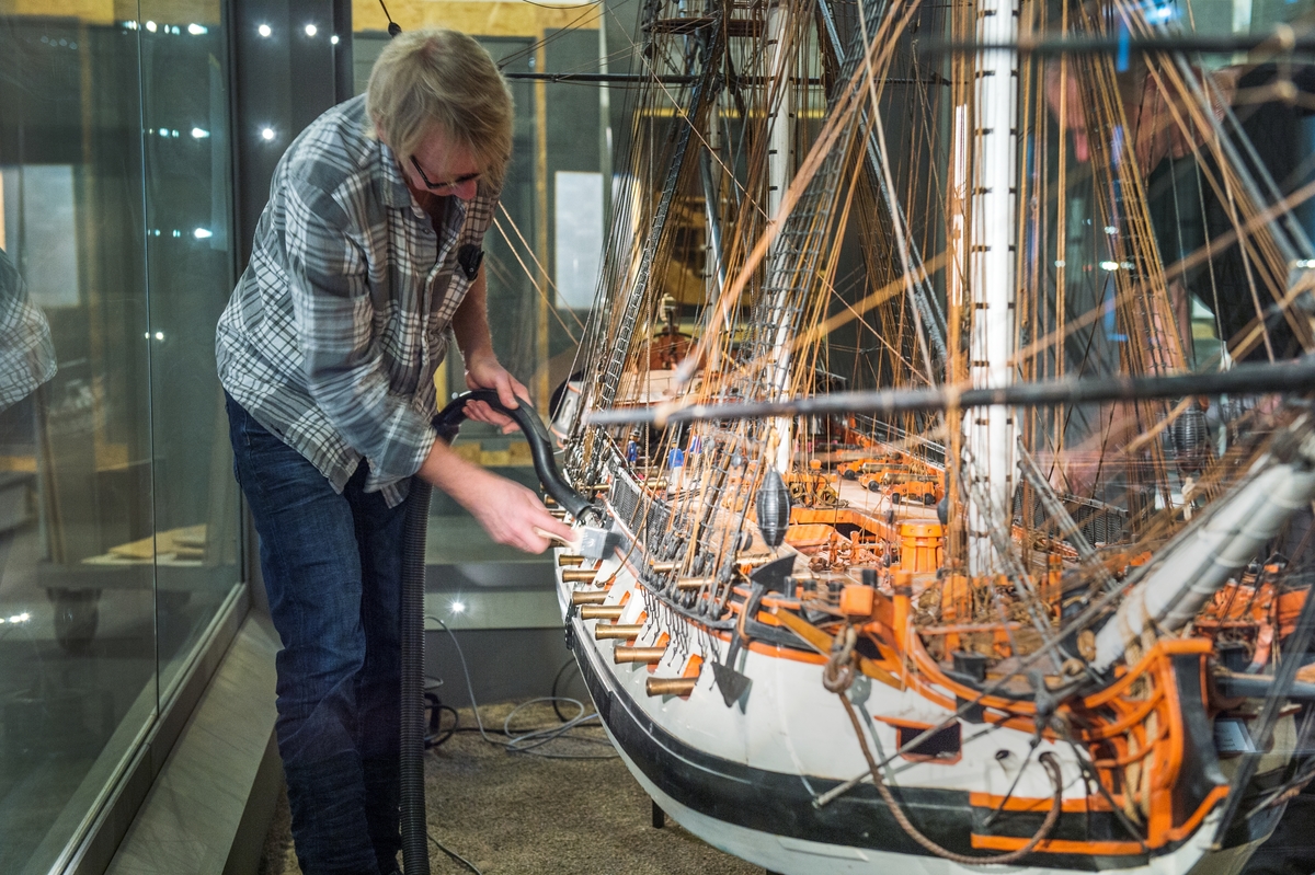 Modellbyggarna Stefan Bruhn och Jan Claeson städar i monter i utställningen Klart skepp.
