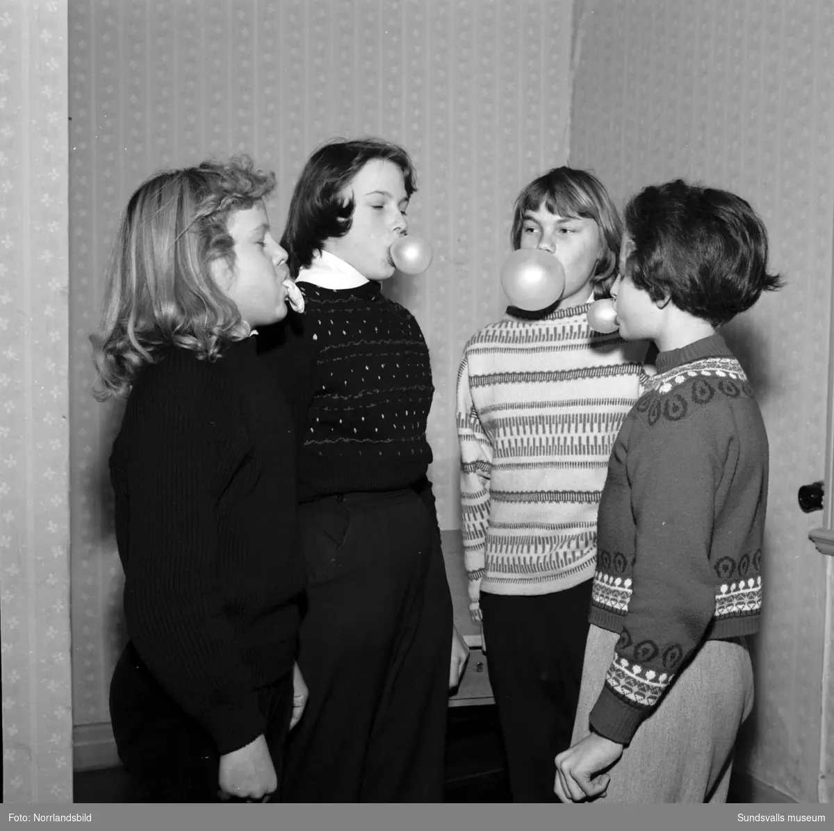 Fyra flickor som blåser tuggummibubblor.