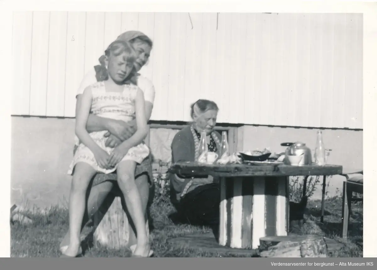 Bilde av to kvinner og en jente, sittende ved oppdekket bord utendørs