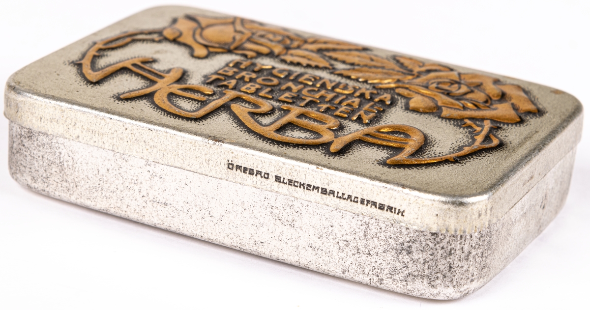 Tablettask i plåt, silverfärgad botten med rosdekor och text i guld: "HYGIENISKA BRONCHIALTABLETTEN HERBA".
