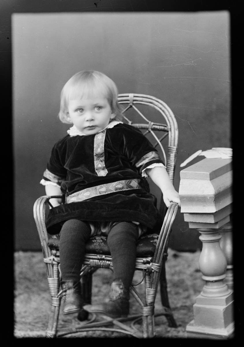 Ateljéporträtt - ett barn sitter i en korgstol, Östhammar, Uppland