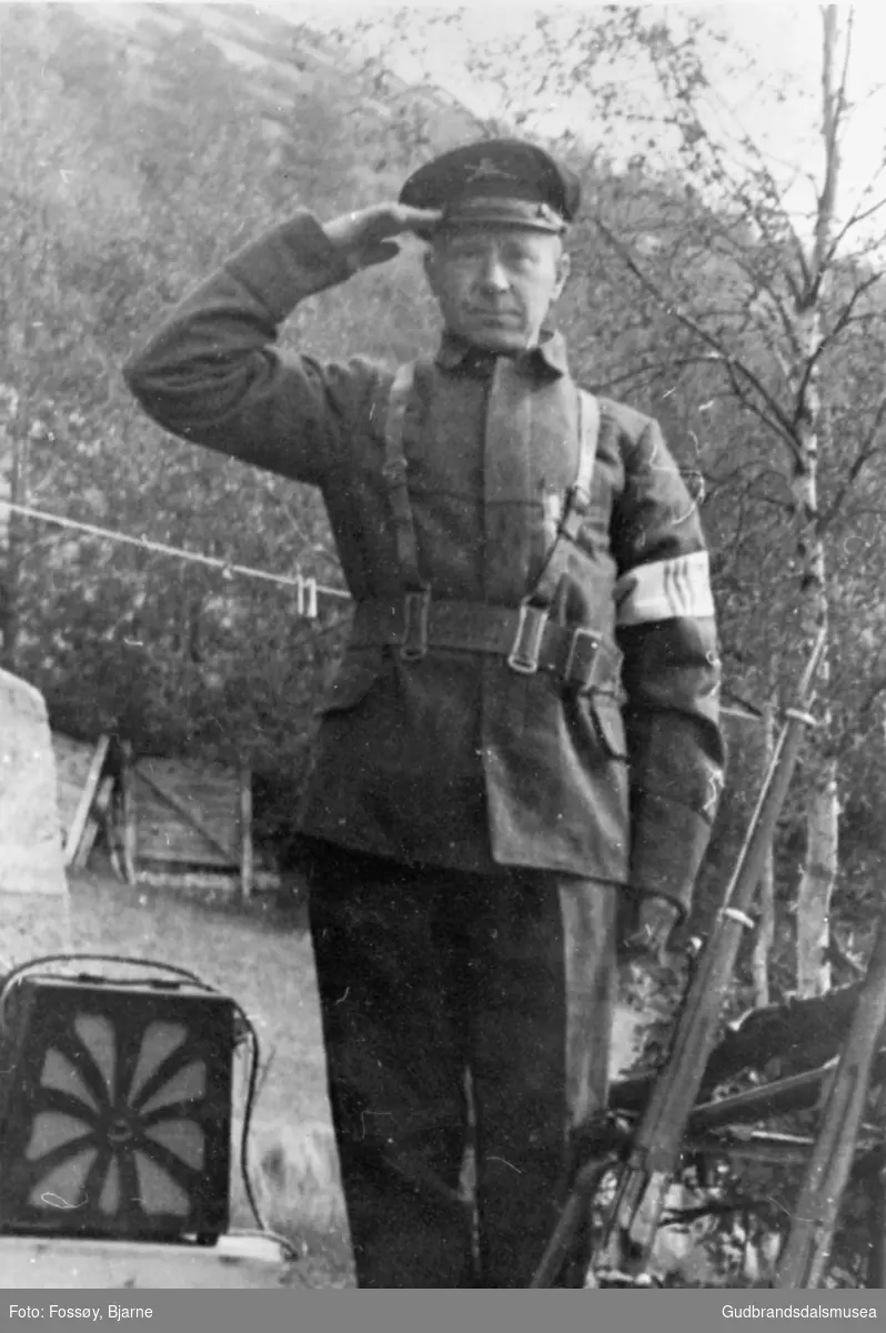 Mann i uniform, Petter Dahl med ein radio laget under krigen, trær i bakgrunnen.

