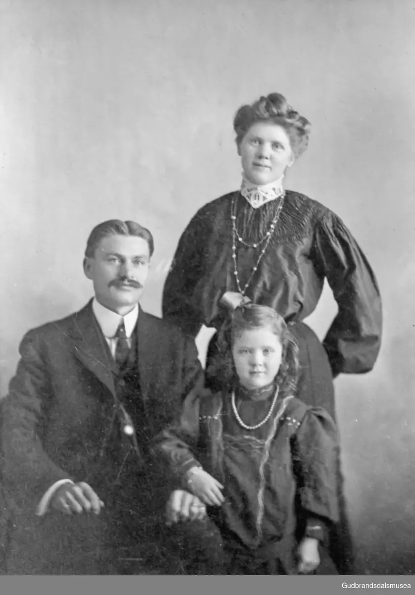 Portrettbilde Enebo, tre personer, kvinne, mann og lita jente, atelierfotografi. Lars reiste til Dakota i 1900.

