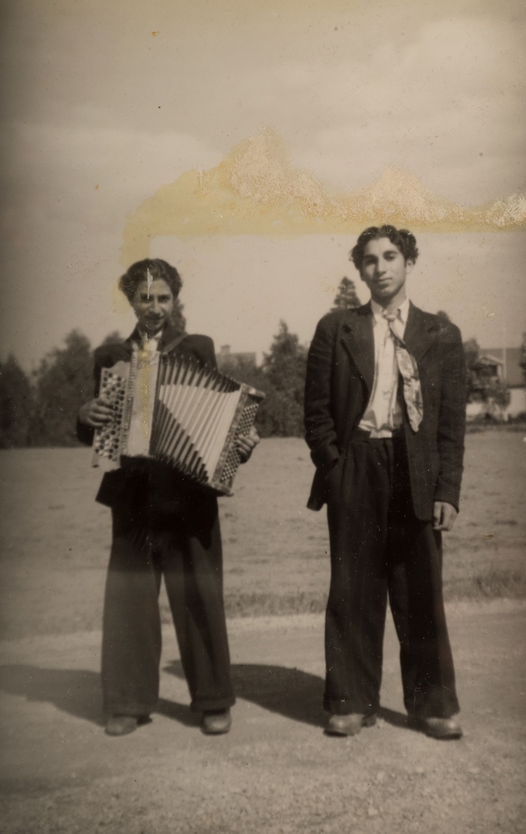 Två romska pojkar står uppställda för fotografering. En av dem håller i ett dragspel.