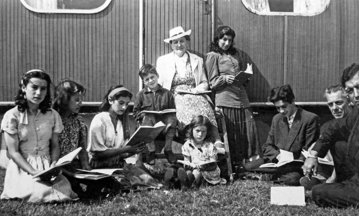 Svensk zigenarmissions skola för romer i Varberg 1948. Framför en vagn sitter en grupp skolelever med böcker i händerna.