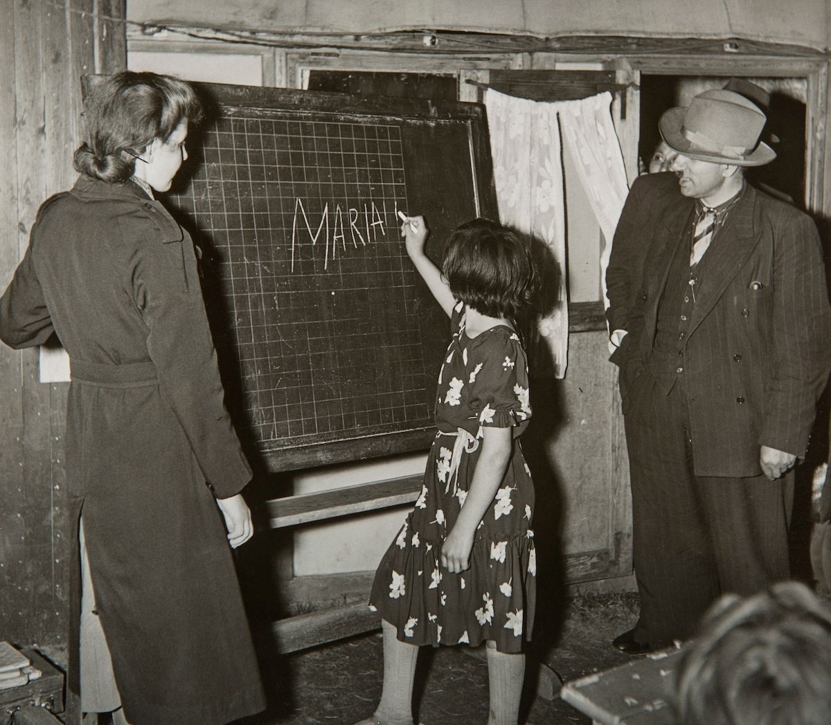 Bilden är tagen i samband med undervisning för romska barn i ett läger i Lilla Sköndal, Stockholm. En flicka skriver sitt namn på den svarta tavlan.