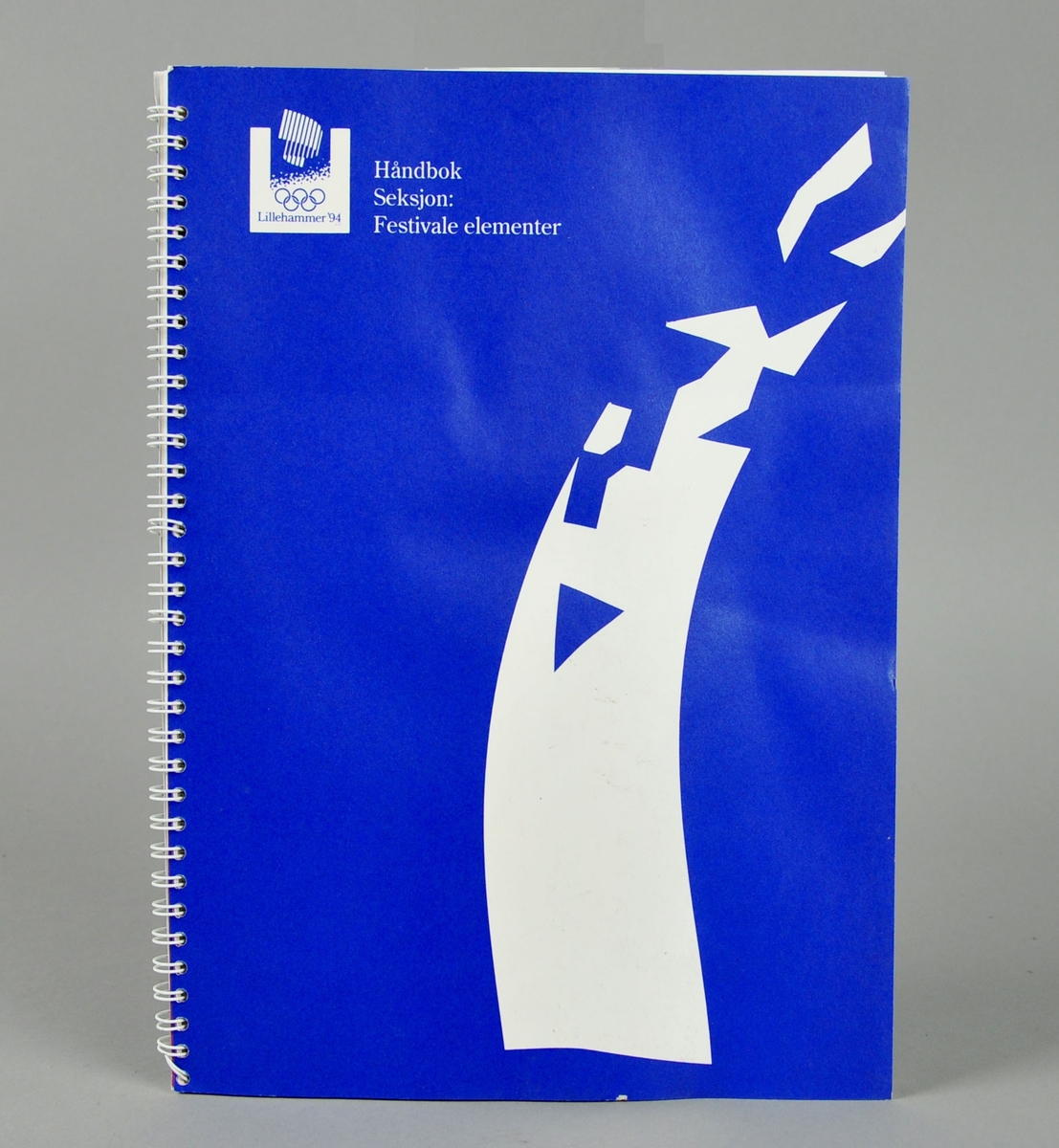 Håndbok for festivale elementer med oversikt over standardiserte elementer som ble brukt til utsmykking av arenaer og andre områder knyttet til Vinterlekene på Lillehammer i 1994.