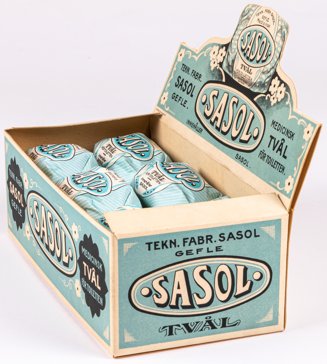 Ask med 11 medicinska tvålar, av märket Sasol. Tvålarna paketerade i papper. Locket till asken kan vikas upp så att asken kan användas för skyltställ.