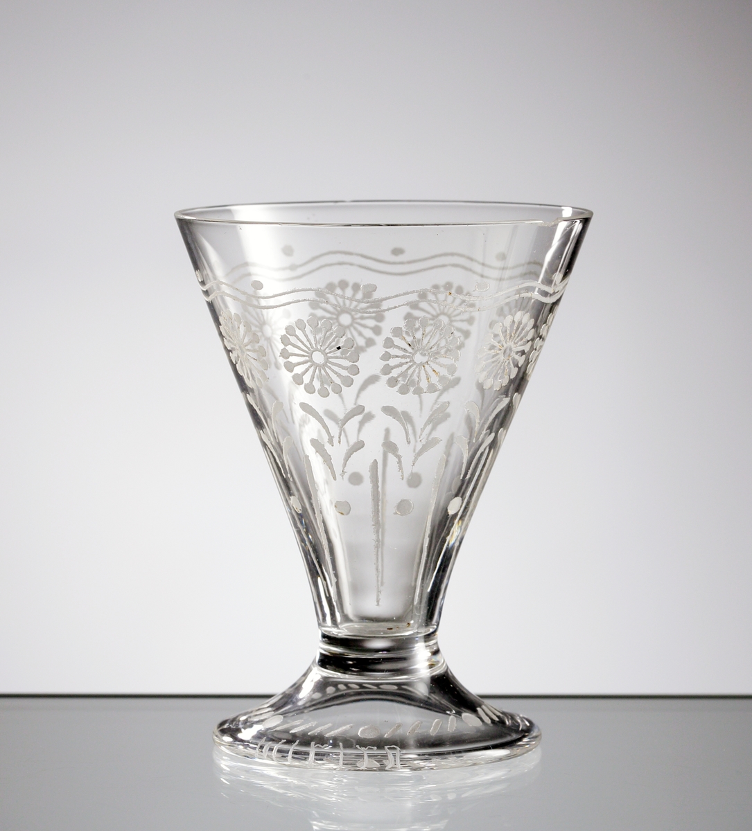 Starkvinsglas i ofärgat klarglas med dekor bestående av stiliserade blommor och blad.