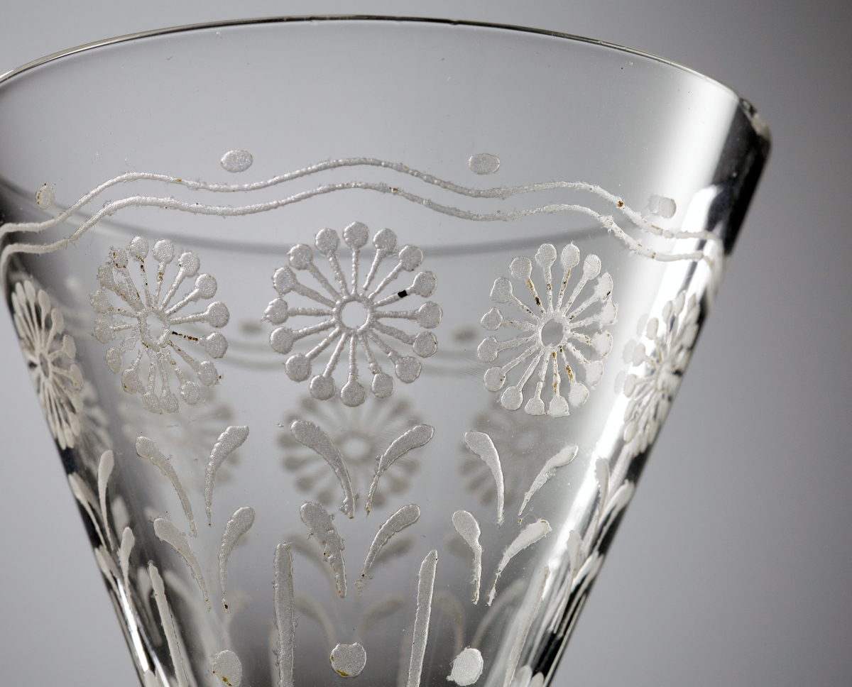 Starkvinsglas i ofärgat klarglas med dekor bestående av stiliserade blommor och blad.