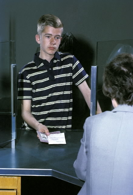 Seriebild H 11. Eleven, 15 år, lämnar fram ett giroutbetalningskort
och Pos-tens legitimationskort, som postkassören tar emot.