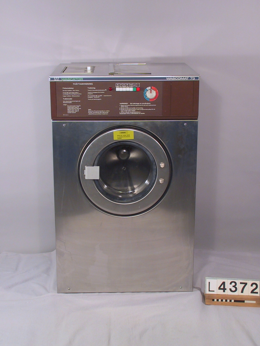 Tvättmaskin för fastighetstvättstuga, tvättbar eller störr hushåll. Maskinen är frontmatad och dimensionerad för 7 kg torr tvätt. Front, lucka och topplåt är i rostfritt. Sidoplåtar och bakplåtar är målade. Programpanelen är i brunt.