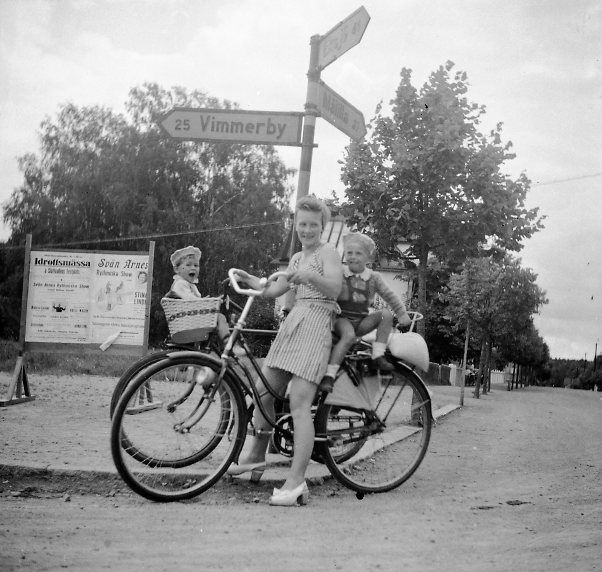 Kvinna med cykel och barn i barnsadlar.