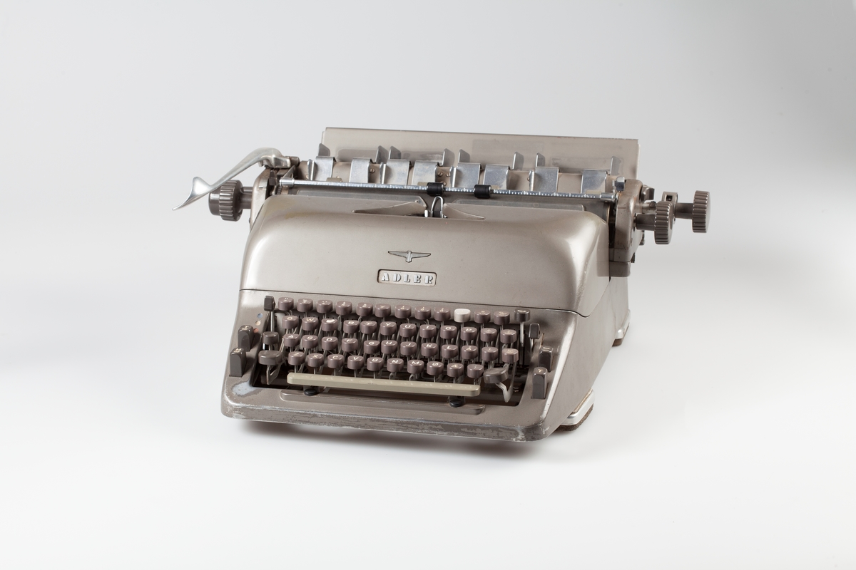 Manuell skrivemaskin med 32 cm valse delt i fire rom for forskjellige etiketter. Preparater til utvortes bruk skulle ha rød etikett og reagenser skulle ha gul etikett.