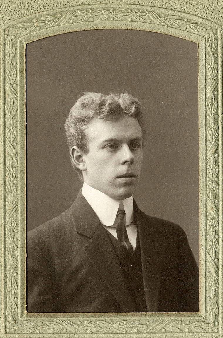 En okänd ung man i kavajkostym med väst och stärkkrage. I nedre högra hörnet syns inpräglat årtal: "1908". 
Bröstbild, halvprofil. Ateljéfoto.