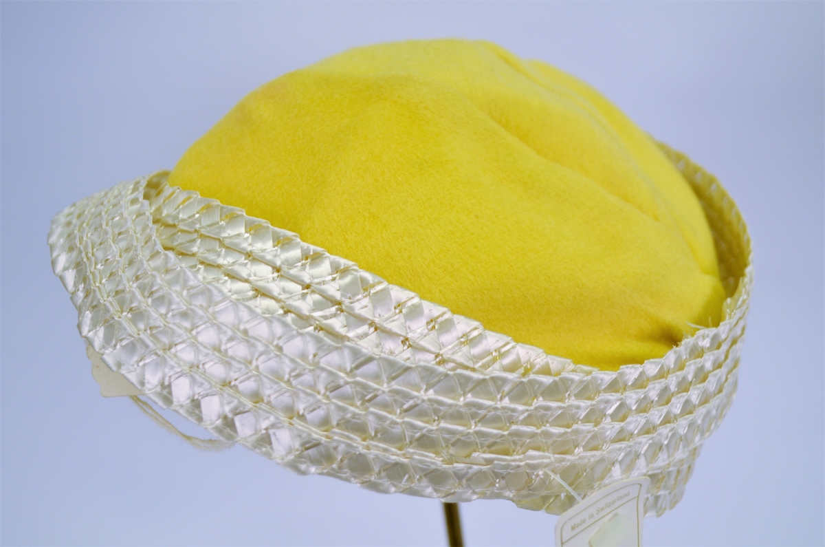 Hatt i gul velour, fóra med stiv netting. Laust "metallband" med merkelapp 8225 Made in Sweitzerland.  42,-