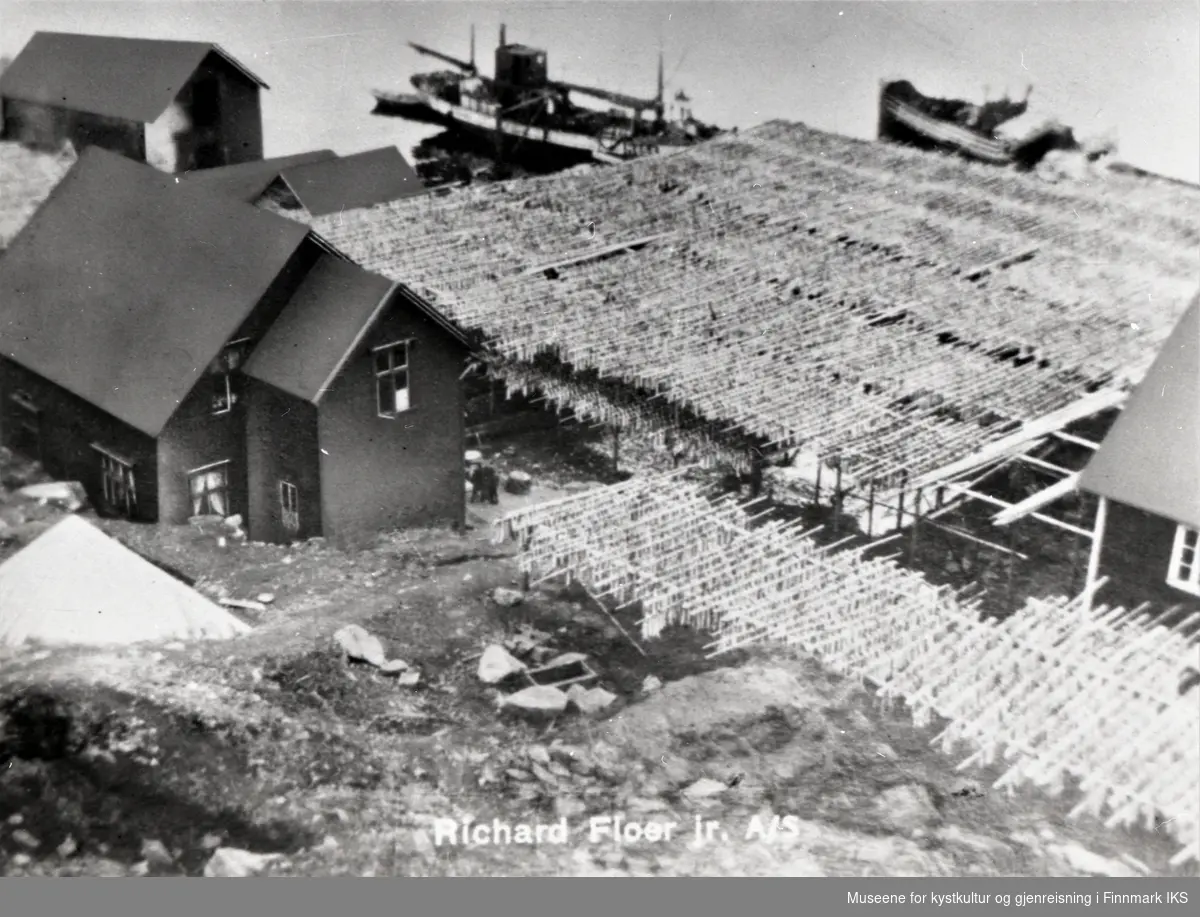 Postkortmotiv. Storbukt. Floerbruket med fiskehjeller, bebyggelse og skip ved kaia. Ca. 1935.