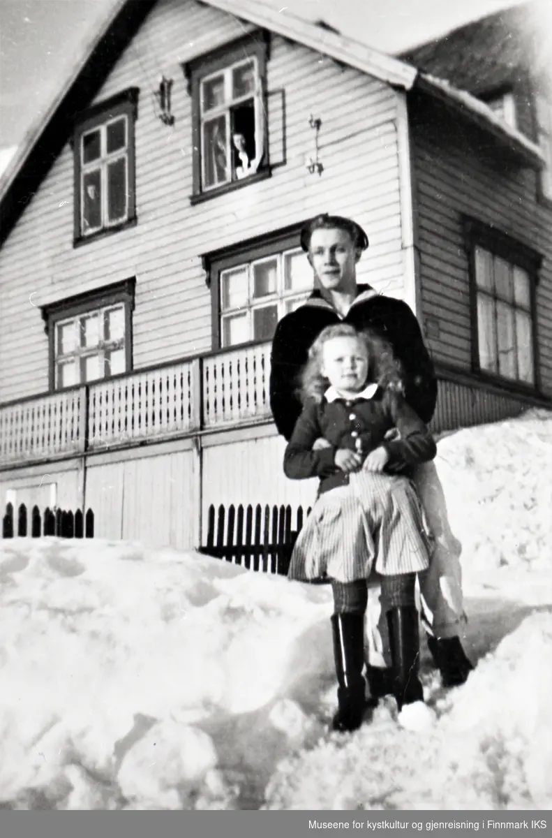Honningsvåg. Inger Jensen og en tysk ung mann foran Korneliussens hus. Ingrid Jensen i vinduet.
