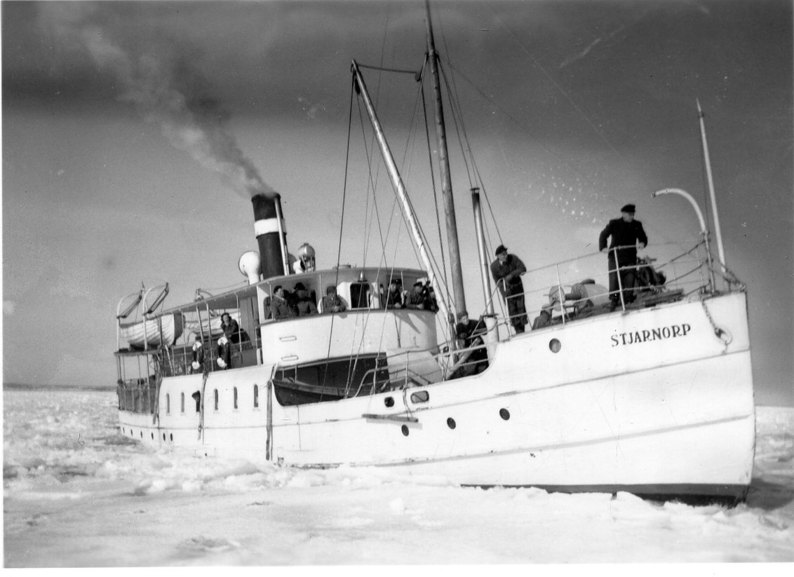 Motoriserade ångbåten M/S Stjärnorp går bland is på Vättern. Män står i fören och håller utkik.