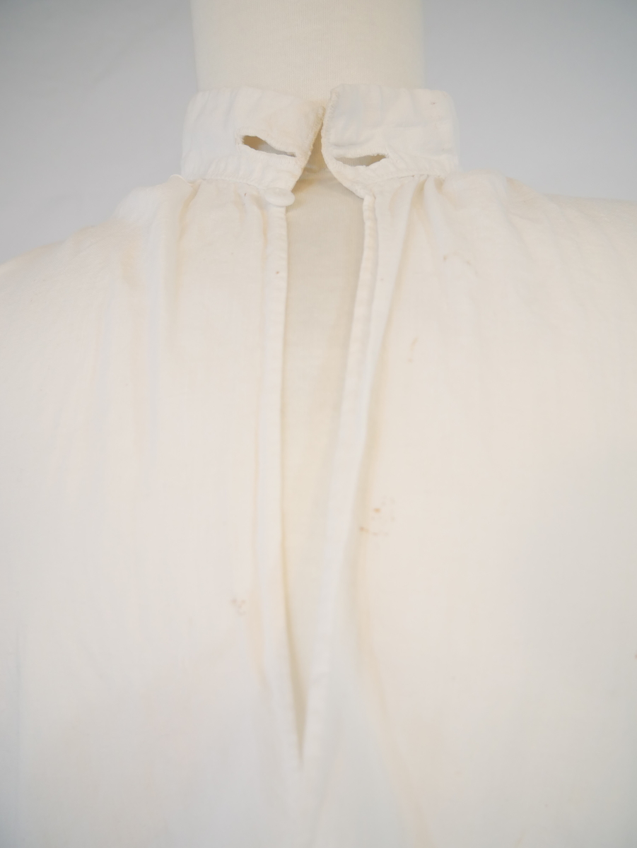 Skjorte i primærsnitt med trekanta kile på skulder. Motfold i kilen, tre motfolder bak og  ei framme ca. 5 cm frå splitten. Rett isydde ermer med kilar og to folder på kvar side. Halvopen, knapp øvst i opningen og to handsydde knapphol på halslinningen. Hemper og krokar på ermlinningane. Splittar i sidene.
Usikkert kva type bunad/drakt skjorta har vore brukt til.
Sjå Andre oppl.; Bunad- og folkedraktrådet si registrering.