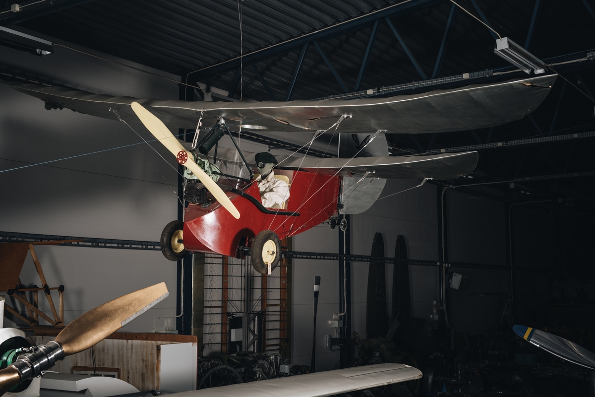 Flygplan kallat "Flygande loppan". Ensitsigt hembyggt propellerflygplan. Motor av märket DKW. Rödmålad flygkropp och silverfärgade vingar. På båda sidor av sidrodret finns målning av en loppa.