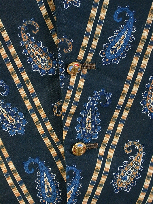 För man. Tryckt mönster, persiskt schalmönster i svart, blått och gult. Enkelknäppning med gul metallknapp.