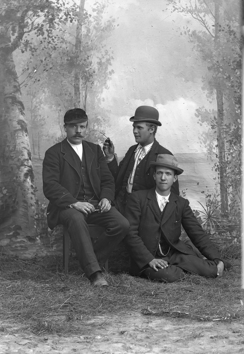 Portrett av 3 menn med dress og hatt, sitter.