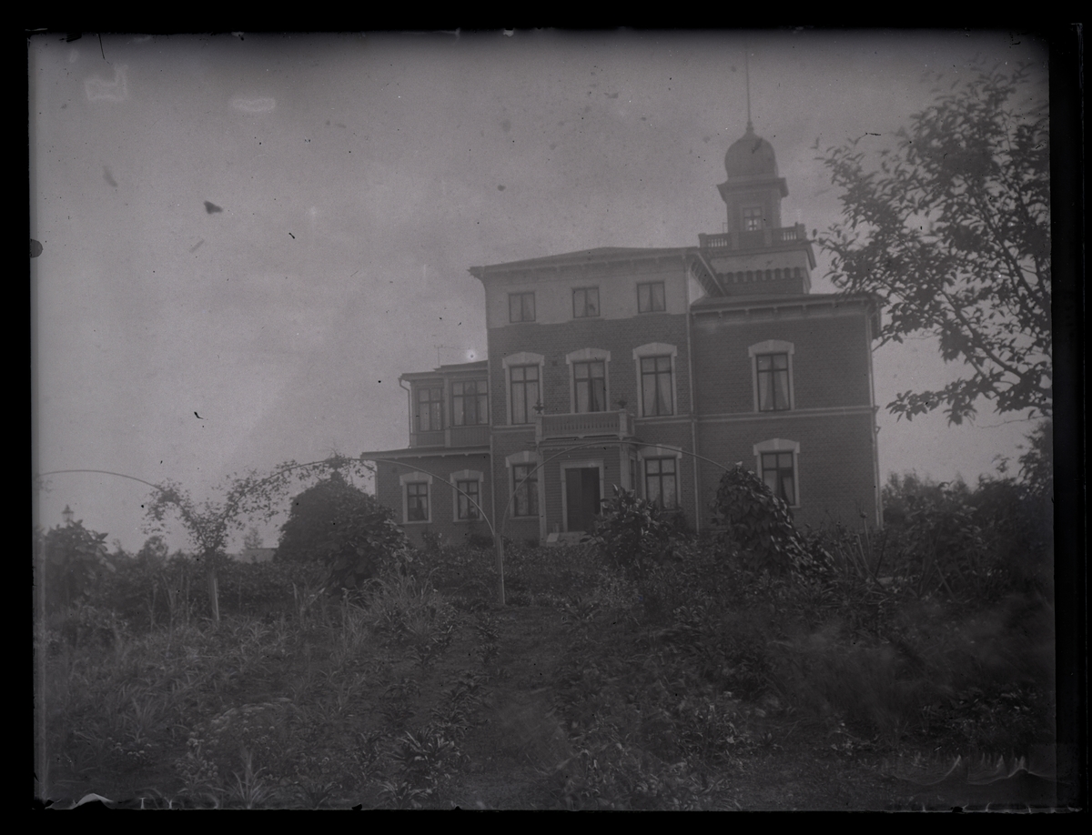 Större bostadshus med torn i trädgård, ca 1910.