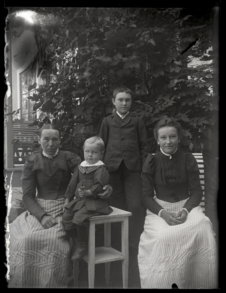 Två damer och två barn i trädgården, ca 1910.