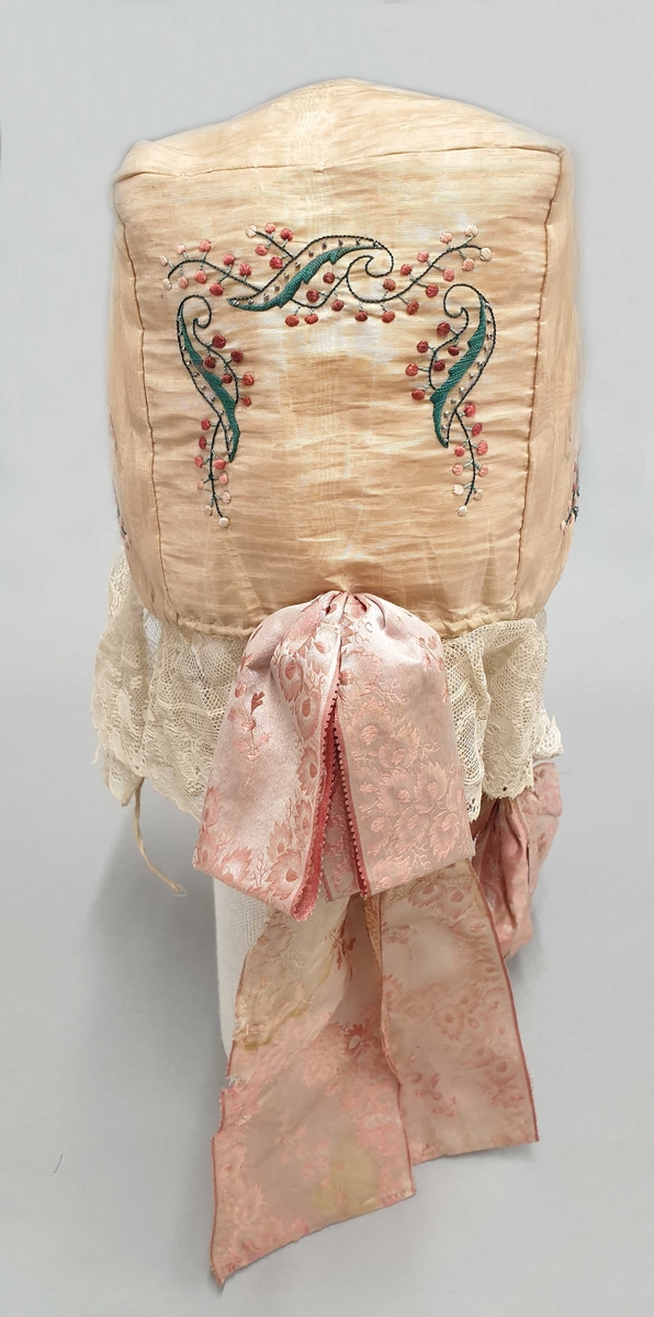 Kyse av gul silke med broderi og perlebroderi, med kniplingsblonde langs kantene, og rosa silkesløyfe.