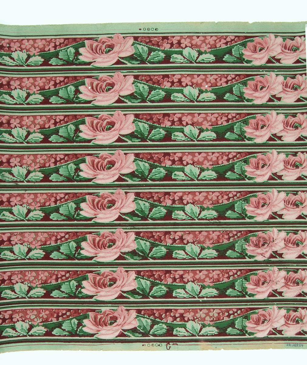 Oskurna tapetbårder med rosor och blomstergirlander i rött, grönt och rosa. Tryckt på obestruken botten av grönt genomfärgat papper, bottenfärgen utsparad i mönstret. Tillverkad av Göteborgs tapetfabrik. IB
