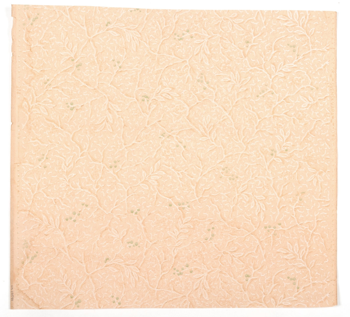 Tapet med yttäckande mönster av blad och grenar i vitt och grönt på gulrosa effektmönstrad botten. Fyra tryckfärger. Tillverkad av Norrköpings tapetfabrik. IB