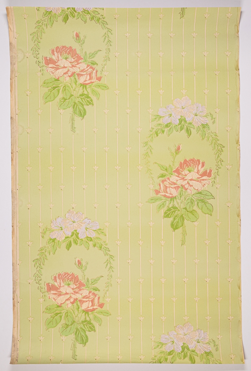 Tapet med diagonalt upprepade rosenbuketter och blomsterkransar i rosa, vitt och grönt mot ljusgrön, randmönstrad fond. Tapeten är tryckt på obestruket papper. Papprets färg framträder genom utsparningar i mönstret.'