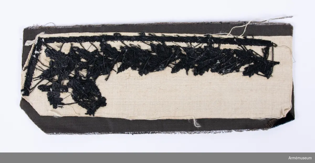 Broderi till krage i svart sammet med svart broderi i cordonnesilke, föreställande lövverk - vartannat lagerblad och vartannat ekblad - och lyra. På baksidan är kragen dubblerat med linnelärft för stadga.