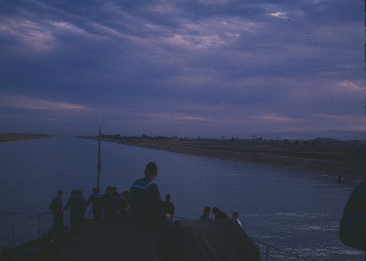 Bilden visar besättningsmän som står på Älvsnabbens förskepp och tittar på Suezkanalen på nattetid.