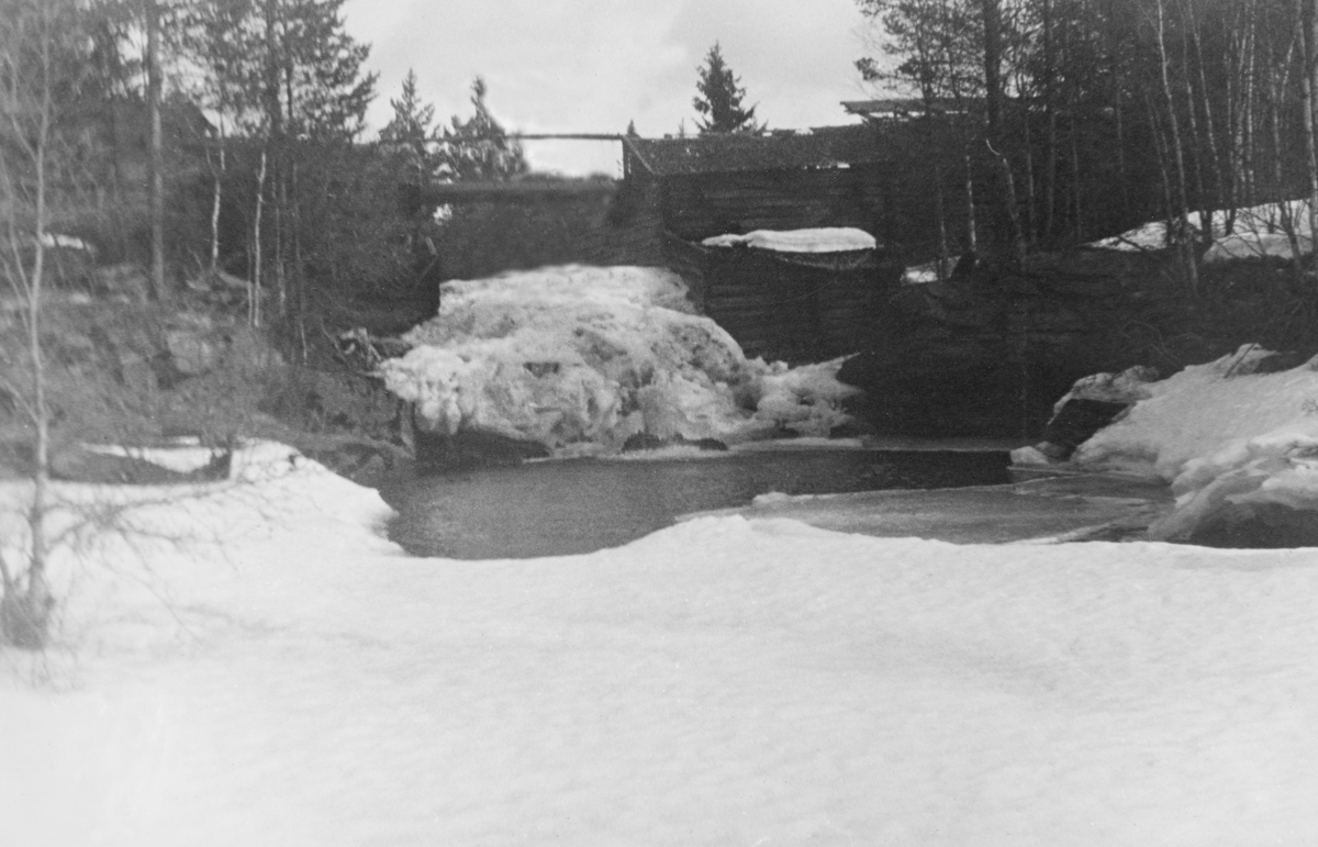Fiskvikrokkdalsdammen i elva Rokka i Rendalen, fotografert på en seinvintersdag i 1943. Landskapet og vassdraget var ennå dekt av snø. Fotografiet er tatt i motstrøms retning, fra en posisjon på den snødekte isen like nedenfor den åpne kulpen ved damåpningens utløp i det nedenforliggende elveleiet. Sjølve damløpet var stengt av en store issvull. Bak krattskogen i forgrunnen skimter vi de overbygde damarmene, en konstruksjon som ikke var så vanlig i Glommavassdraget. Mer informasjon om Fiskvikrokkdalsdammen finnes under fanen «Andre opplysninger».